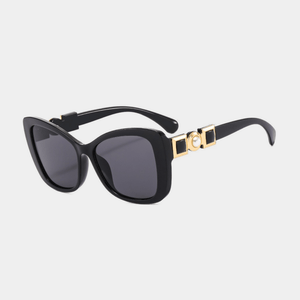 Black sunglasses with gold accents on a light gray background