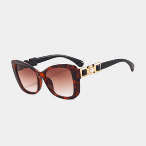Sunglasses with tortoiseshell frame and brown gradient lenses on a light gray background