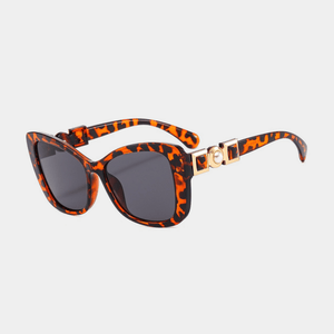 Sunglasses with tortoiseshell frame and gold accents on a light gray background