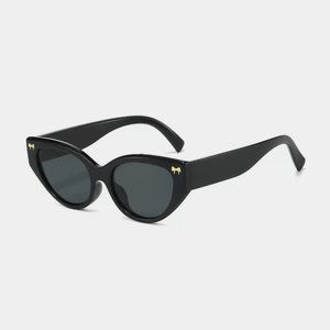 Black sunglasses with gold accents on a light gray background