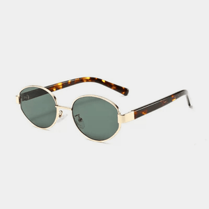 Sunglasses with gold frame and tortoiseshell accents on a light gray background