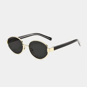 Sunglasses with gold frame and black lenses on a light gray background