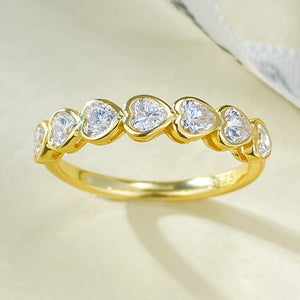 Gold ring with heart-shaped diamonds on a light background