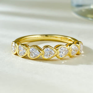 Gold ring with heart-shaped diamond stones on a light background