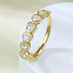 Gold ring with heart-shaped diamonds on a light background