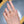 Hand wearing a diamond ring with a blurred background