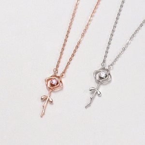 Two rose gold and silver necklaces with floral pendants on a light gray background