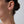 Gold chain earring worn by a person with a neutral background