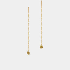 Gold threader earrings with rose-shaped charms on a light gray background