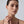 Woman wearing gold earrings with a plain background
