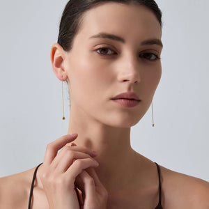 Woman wearing gold earrings with a plain background