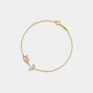 Gold bracelet with pink and clear gemstones on a light gray background