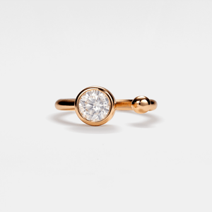 A round cut moissanite ring with a hypoallergenic finish on a sterling silver band, with a visible gold plating on the band.