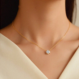 Gold necklace with a diamond pendant on a model wearing a beige top.