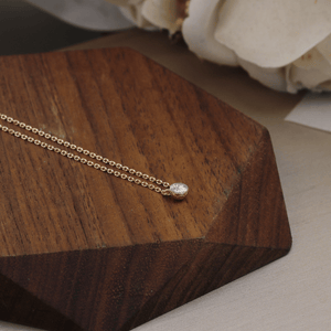 Gold necklace with a small pendant on a wooden surface
