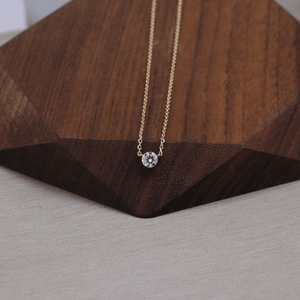 Gold necklace with a diamond pendant on a wooden surface