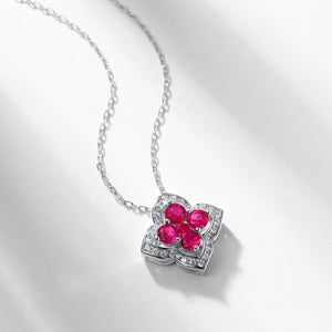 Silver necklace with a heart-shaped pendant featuring red gemstones on a light gray background