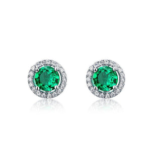 Pair of emerald green gemstone earrings with silver halo on a white background