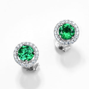 Pair of emerald green gemstone earrings with silver halos on a white background
