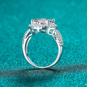 Silver ring with a large central gemstone on a teal background
