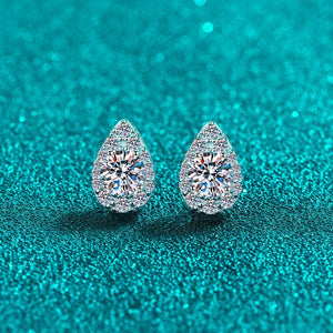 Teardrop-shaped diamond earrings on a teal glitter background