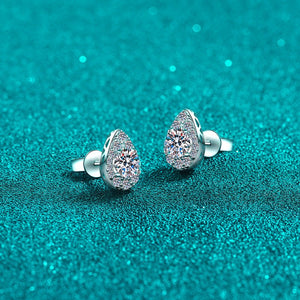 Teardrop-shaped earrings with gemstones on a teal glittery background