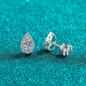 Teardrop-shaped diamond earring on a turquoise glittery background