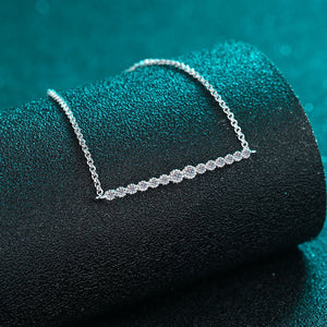 Silver necklace on a black cushion with a teal background