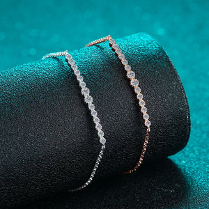 Two diamond bracelets on a black stand with a teal background