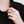Hand wearing a silver ring with a colorful gemstone against a black background