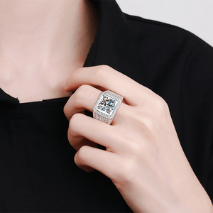 Hand wearing a silver ring with a colorful gemstone against a black background