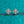 Pair of gold and moissanite earrings on a teal glittery background