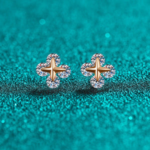 Pair of gold and moissanite earrings on a teal glittery background