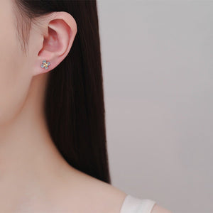 Close-up of a person wearing star-shaped moissanite earrings with a neutral background