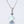 Two round opal charm necklaces with gold plating on a white background, one with a blue opal and the other with a white opal, both on silver chains.