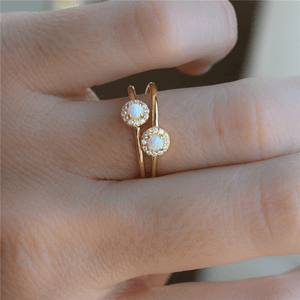 Gold rings with opal stones on a person's finger