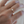 Gold ring with a gemstone on a person's finger against a blurred background