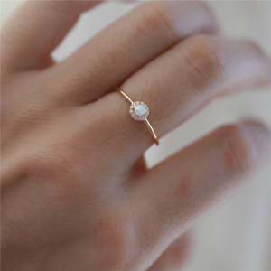 Gold ring with a gemstone on a person's finger against a blurred background