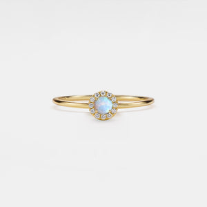 Gold ring with a central gemstone on a light gray background