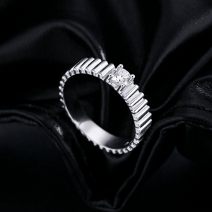 Silver ring with a diamond on a black fabric background
