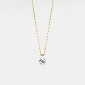 Gold necklace with a diamond pendant on a light gray background