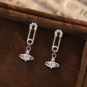 Silver earrings with a unique design on a brown fabric background