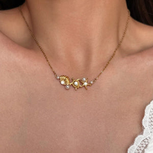 Gold necklace with starfish and pearl design on a person's neck