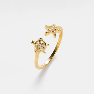 Gold ring with sea turtle and starfish design on a white background