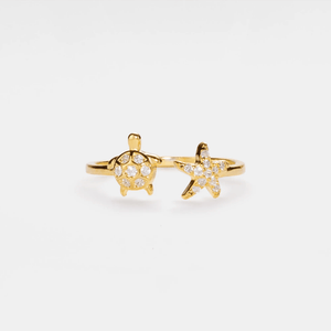 Gold ring with sea turtle and starfish design on a white background
