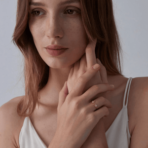 Model wearing a gold ring with sea turtle and starfish design on a white background
