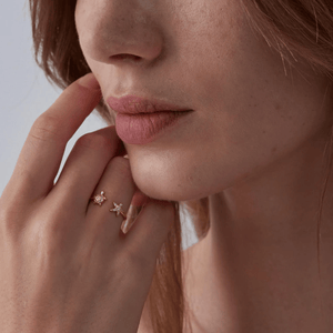 Model wearing a gold ring with sea turtle and starfish design on a white background