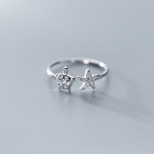 Silver turtle-shaped rings on a gray background.
