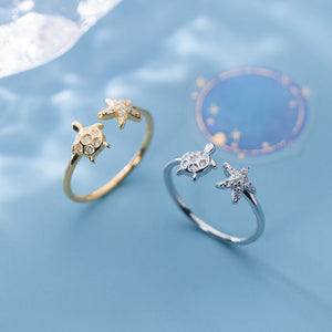 Two turtle-shaped rings, one gold and one silver, on a blue background.