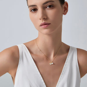 Woman wearing a delicate gold necklace with a white background